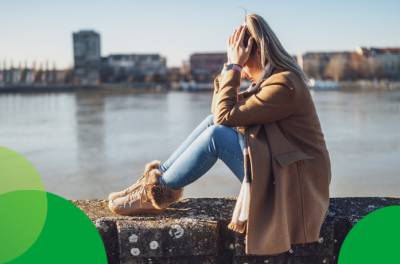 Nuori nainen istuu kalliolla ja kärsii päänsärystä. Farmasisti kivun itsehoidon asiantuntija.